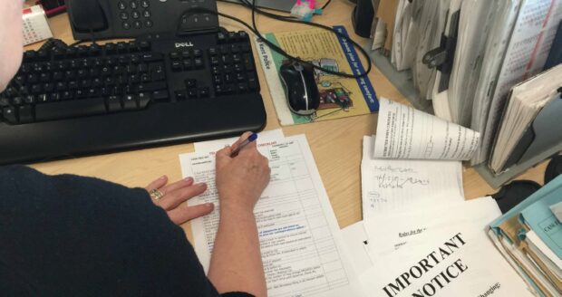 Filling in paperwork in front of a desktop computer