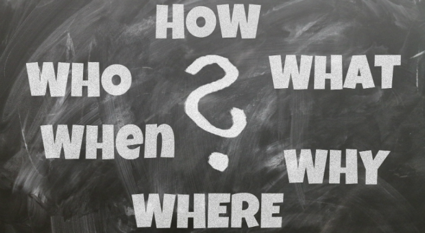 Blackboard with the words who, what, when, where, why and how written in chalk.